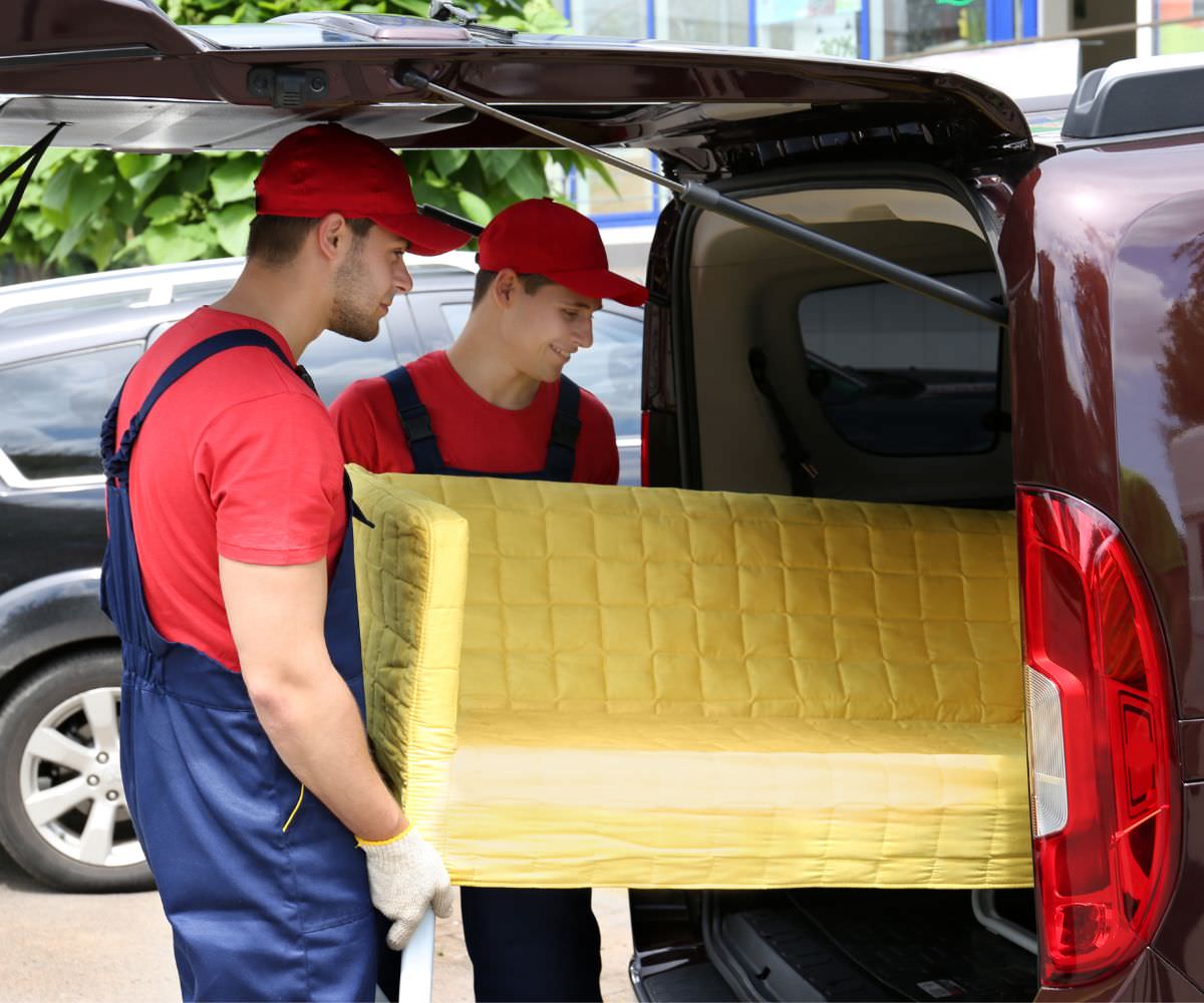 Umzugshelfer laden ein gelbes Sofa in einen Transporter – Preiswert umziehen Worms