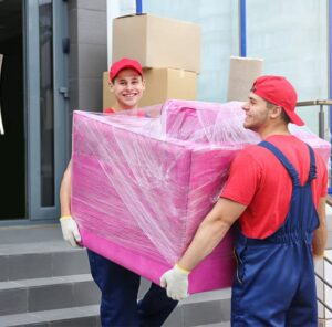 Zwei Umzugshelfer tragen ein in Folie gepacktes Möbelstück – Umzug in Worms