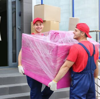 Zwei Umzugshelfer tragen ein in Folie gepacktes Möbelstück – Umzug in Worms